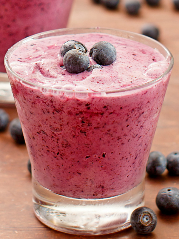 blueberry lemon smoothie in a glass garnished with fresh blueberries and more fresh blueberries scattered around