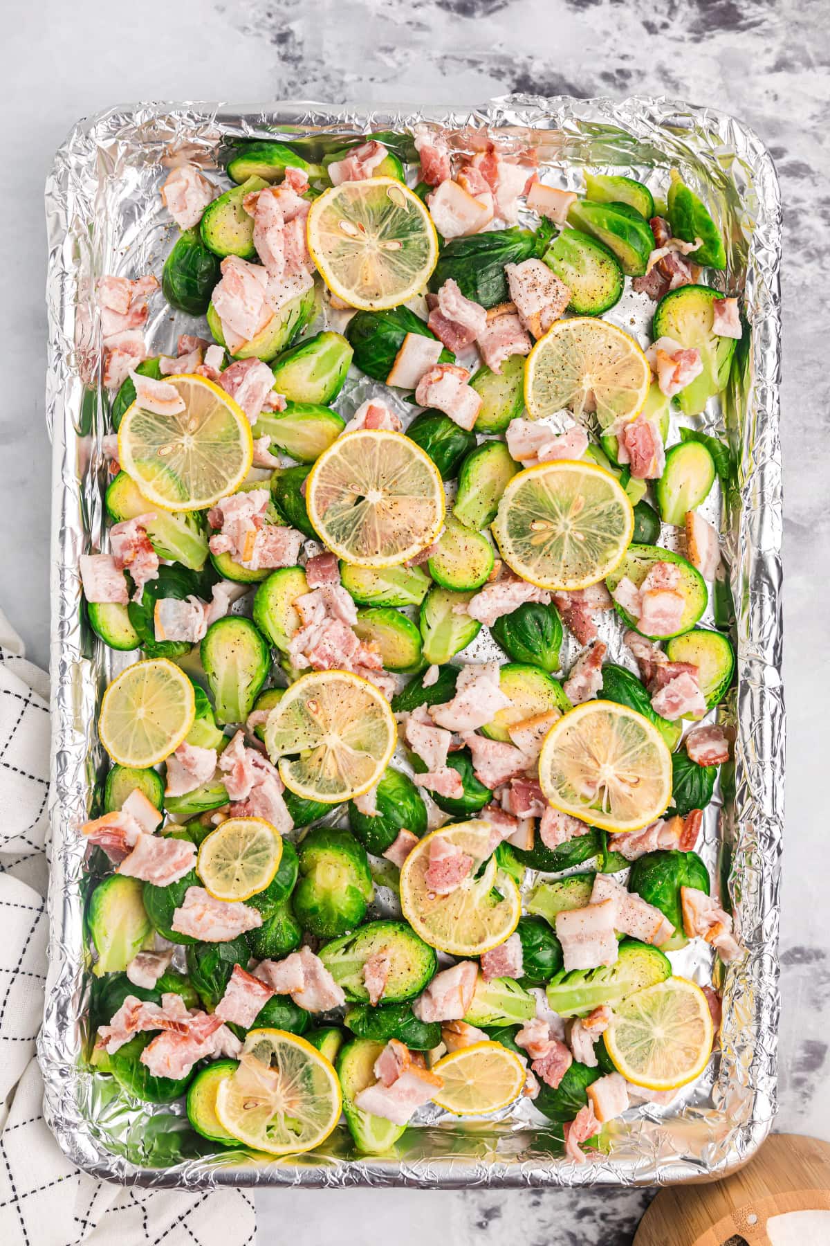 sheet pan of brussels sprouts with lemon and bacon ready for oven