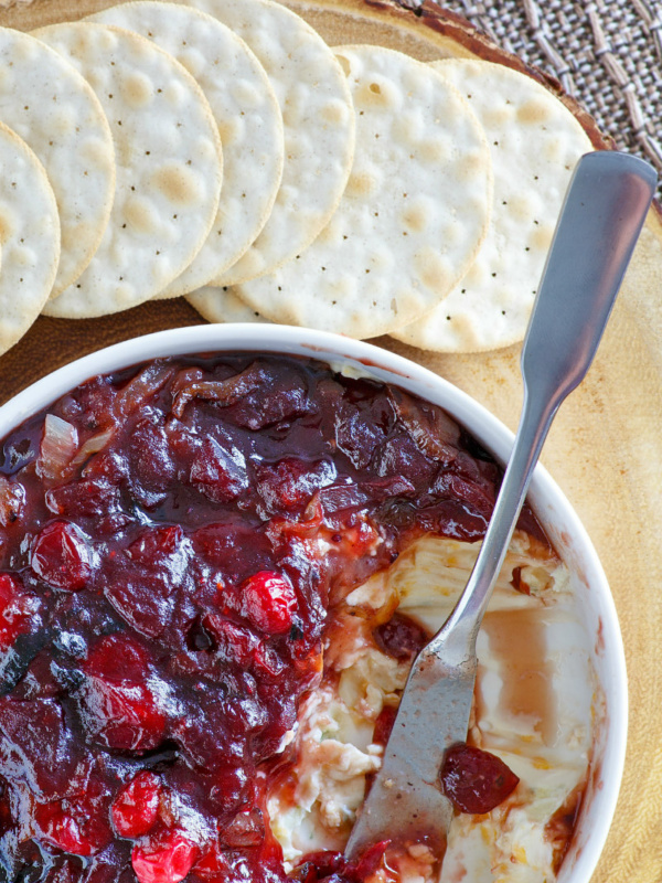 close up of white bowl of cranberry cheese spread served with crackers