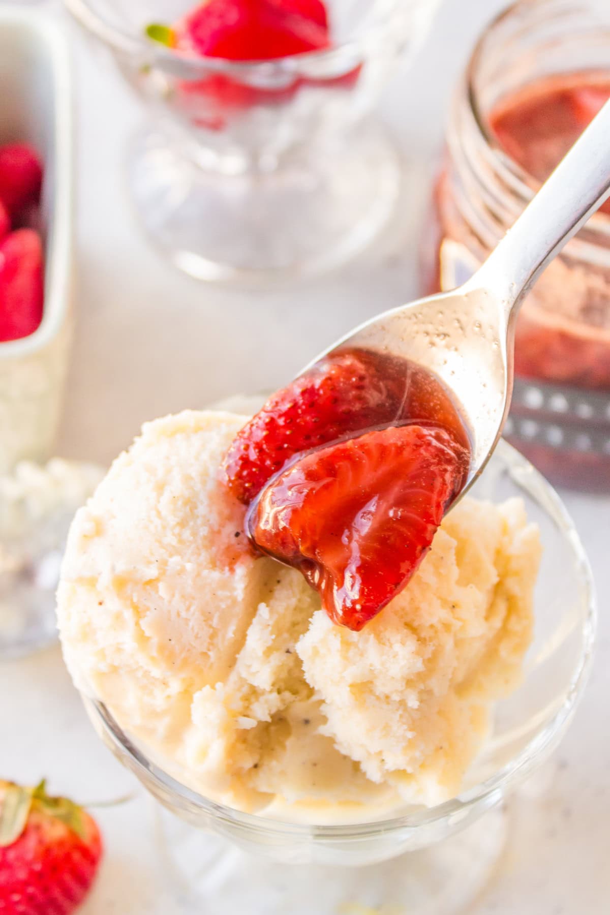 spooning balsamic strawberry sauce onto vanilla ice cream in dish