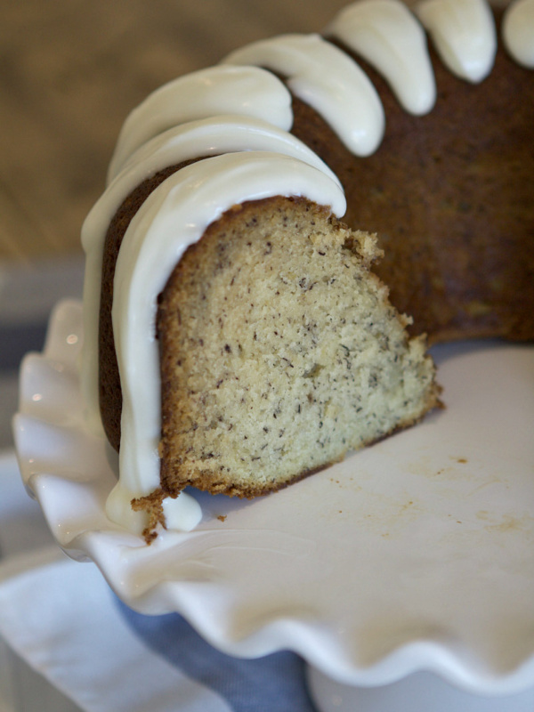 banana bundt cake on a white serving platter. Cake is cut into to see the inside.