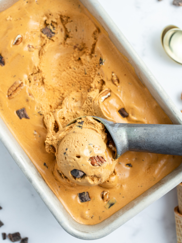 caramel chocolate nut ice cream in a tub with a scoop