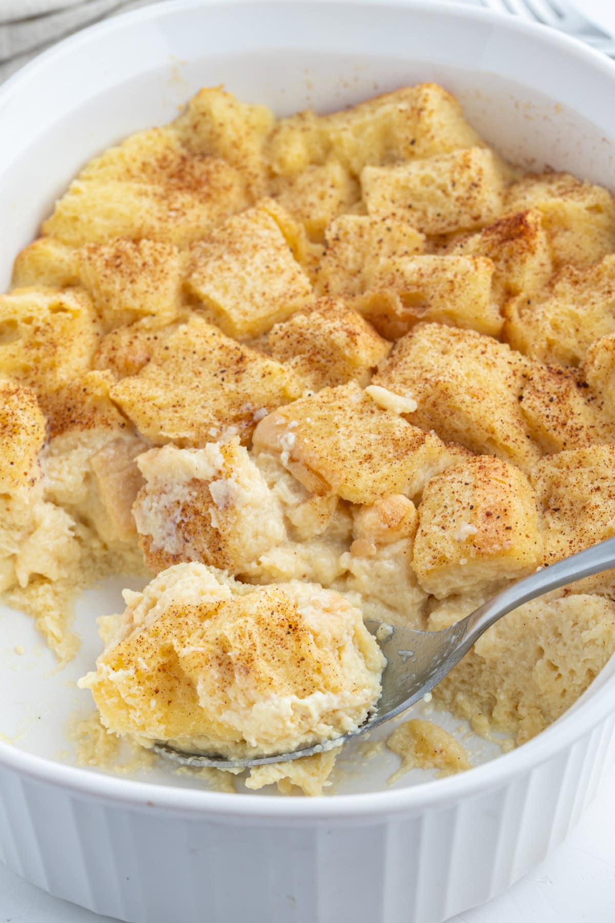 spooning custard bread pudding out of dish