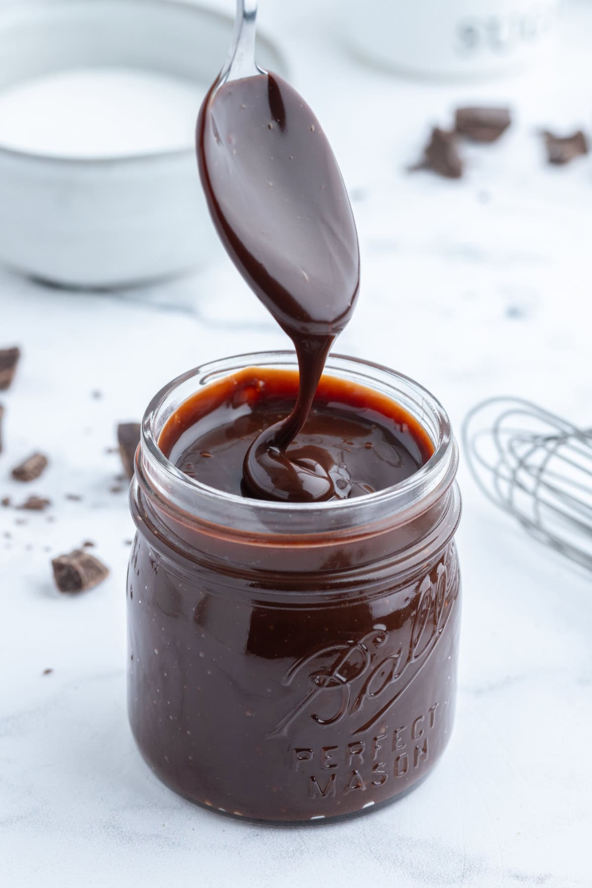 spoon drizzling hot fudge into jar