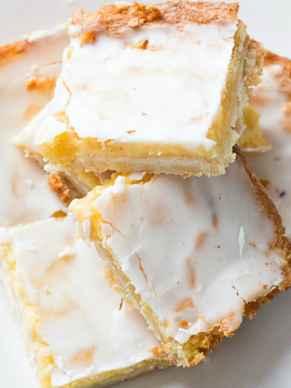 lemon bars stacked haphazardly on a white plate