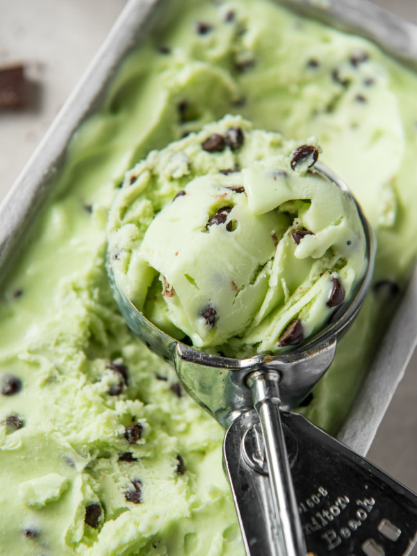 scooper with mint chocolate chip ice cream in it sitting on top of the ice cream container