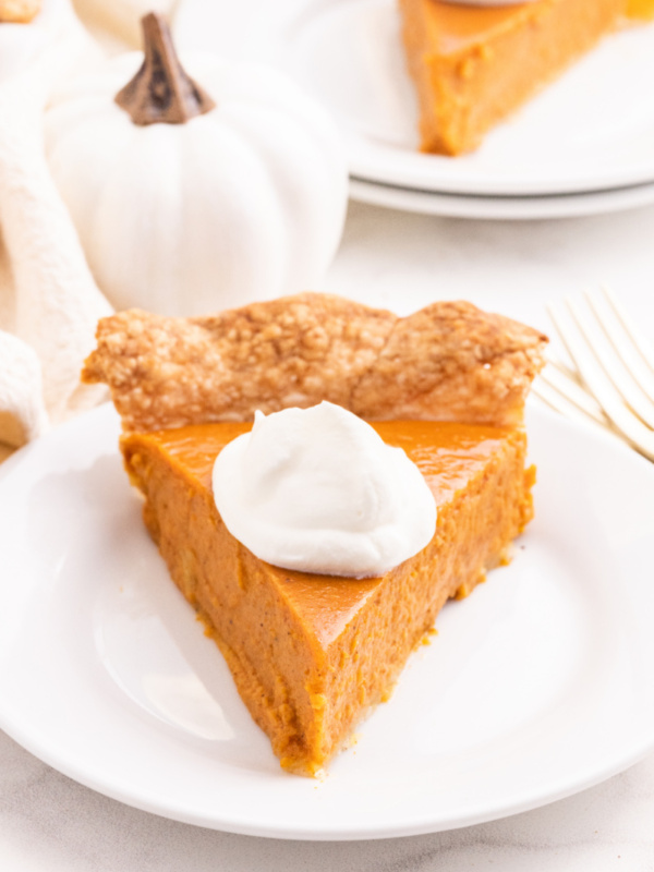 slice of pumpkin pie with whipped cream on plate