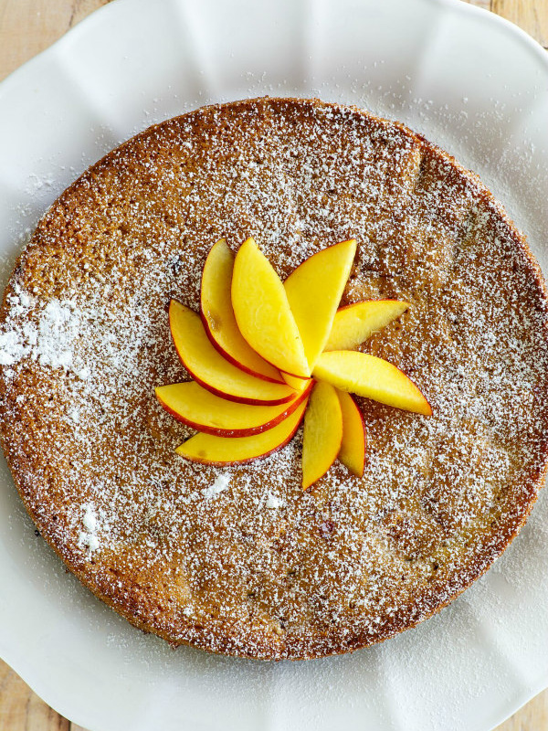 overhead shot of nectarine coffee cake displayed on a white plate with sliced nectarine on top