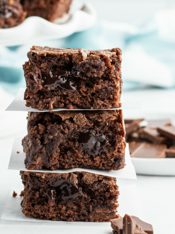 3 stacked brownies with chopped chocolate in the forefront