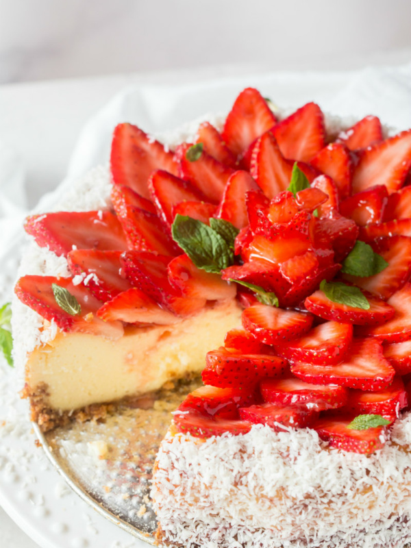 strawberry coconut cheesecake on platter with a slice removed