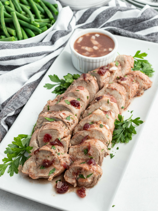 sliced cranberry pork tenderloin on a white platter