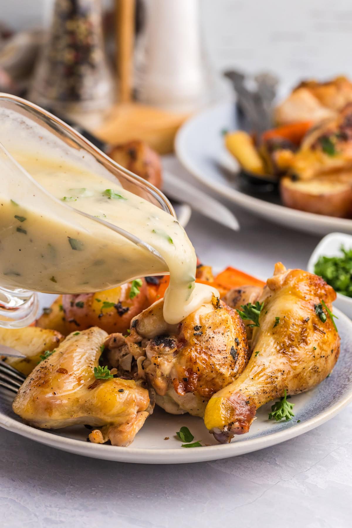 pouring gravy onto easy roast chicken dinner on plate