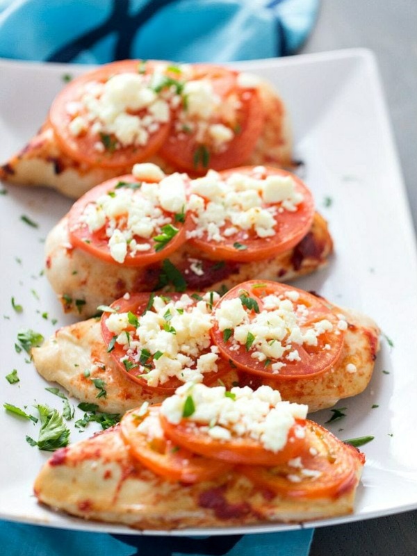 feta topped broiled chicken on a white plate