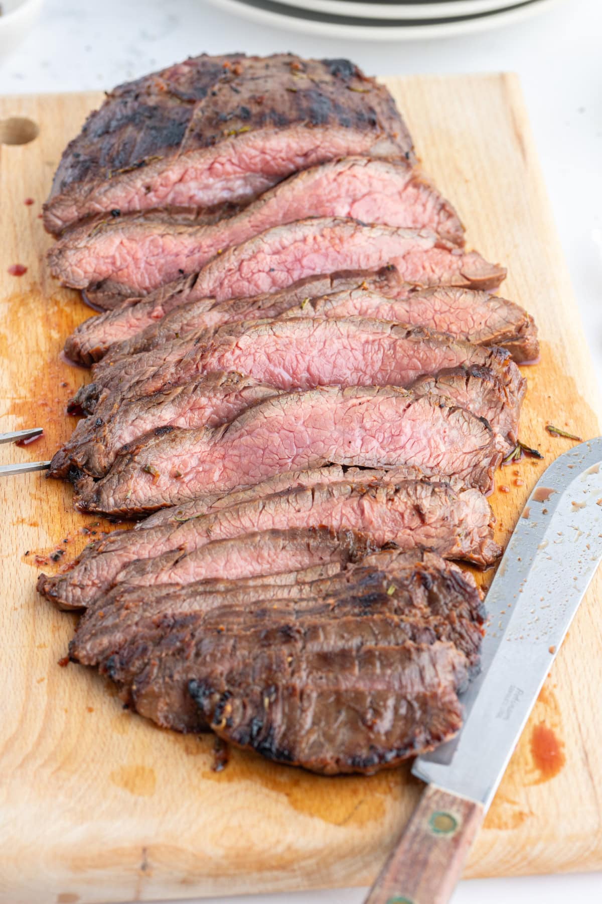 grilled flank steak with rosemary marinade sliced on board