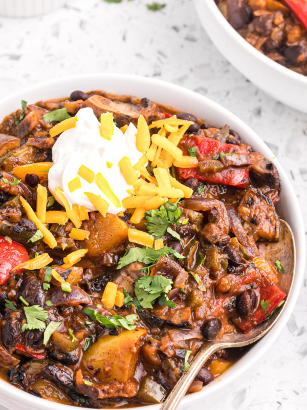 grilled vegetable chili in a bowl garnished with sour cream and cheese