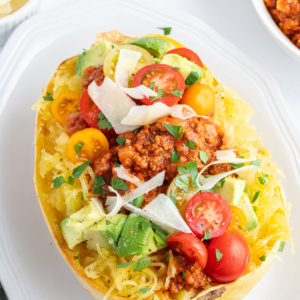 spaghetti squash filled with spicy meat sauce and garnishes