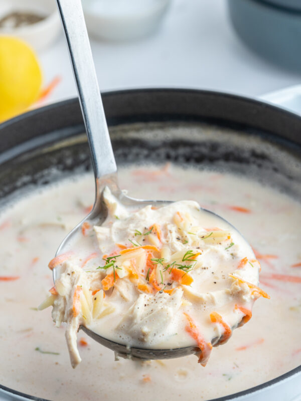 ladle full of greek orzo and chicken soup over pot of soup