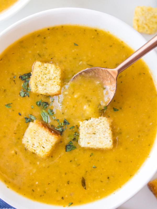 bowl of zucchini fresh oregano soup topped with croutons and spoon