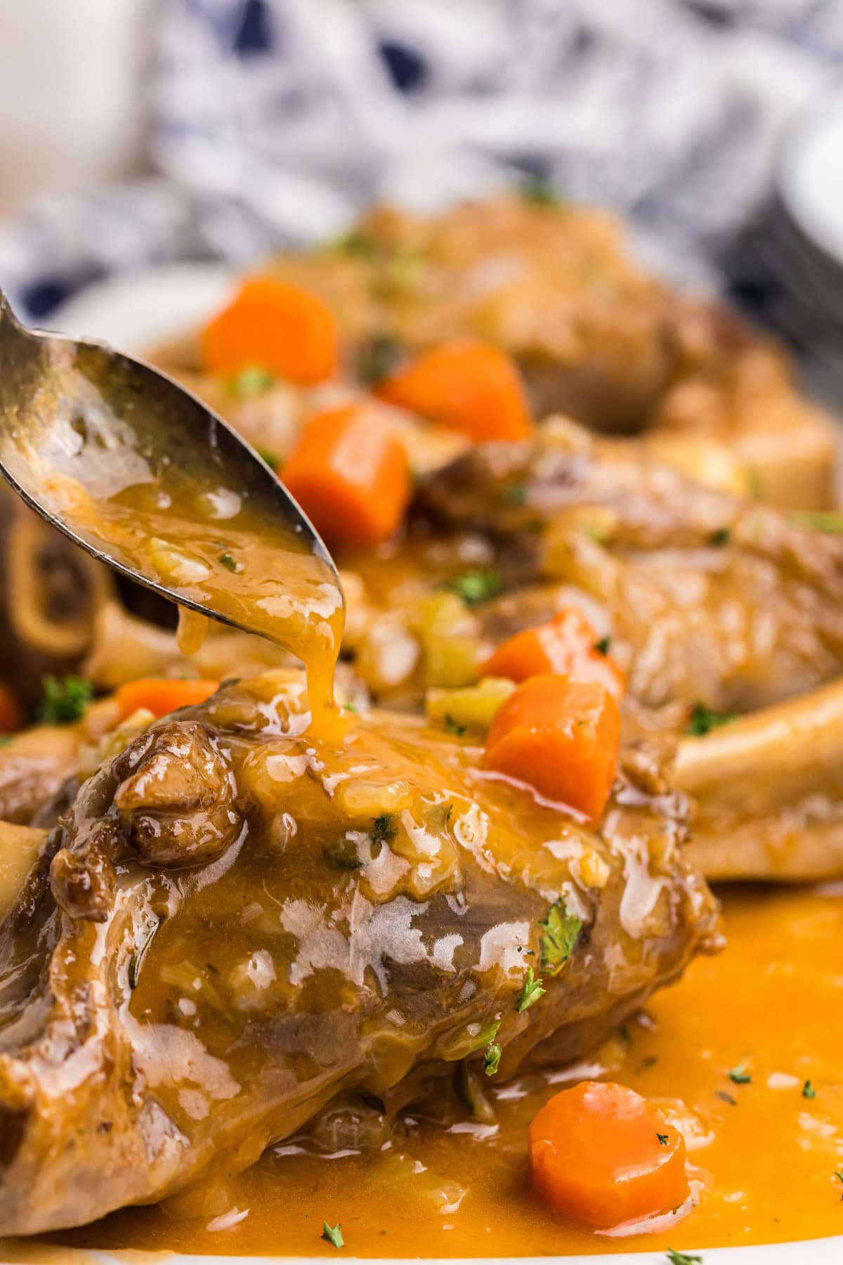 spooning sauce onto braised lamb shank