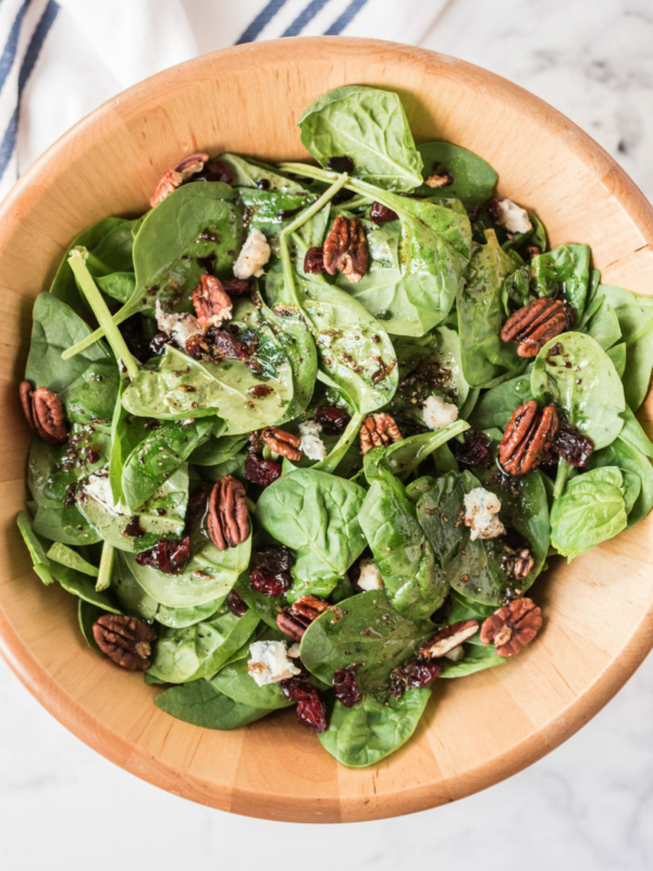 cranberry spinach salad in wood bowl