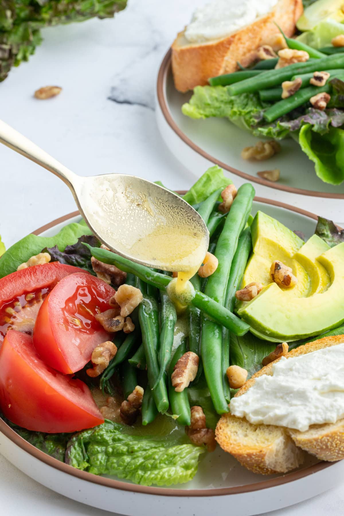 spooning dressing onto french goat cheese salad