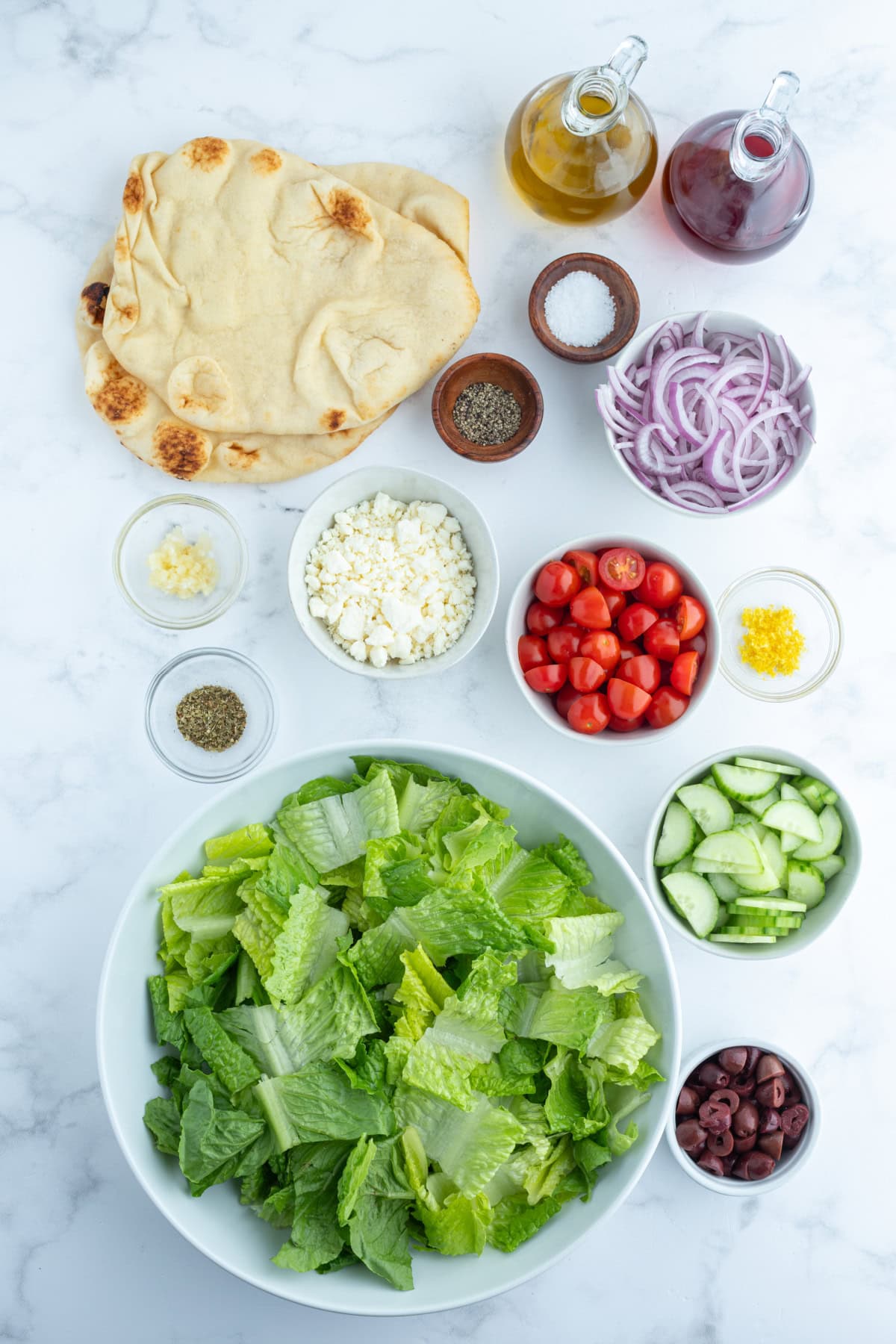 ingredients displayed for making greek salad with seasoned flatbread