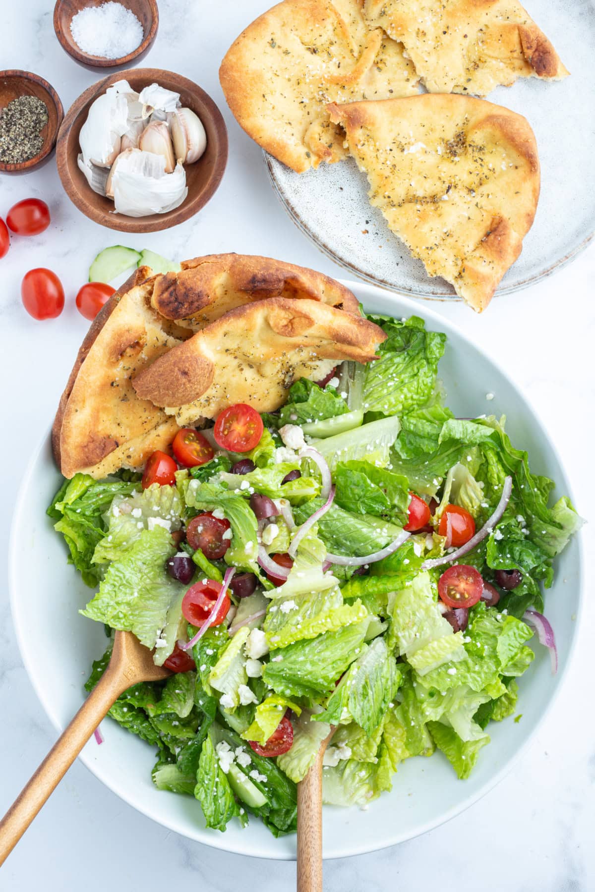 overhead shot of greek salad with seasoned flatbread in a bowl
