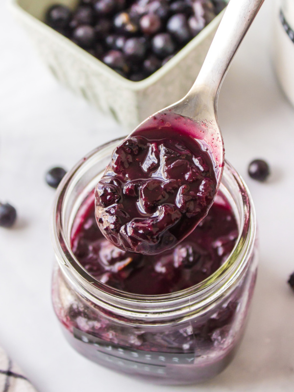 spooning hot blueberry sauce out of a jar