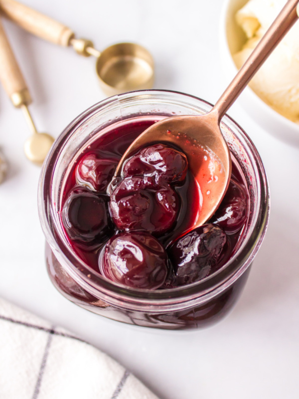 spooning out hot cherry sauce out of jar