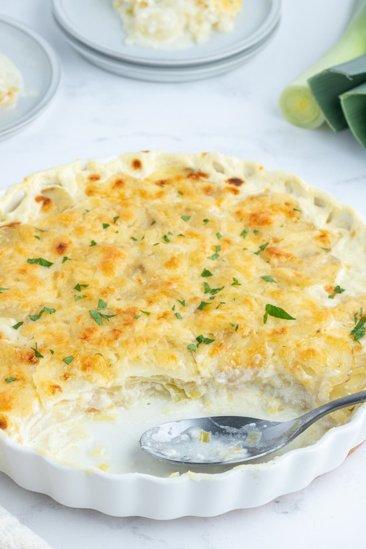 potato leek gratin in casserole dish with large chunk out of it