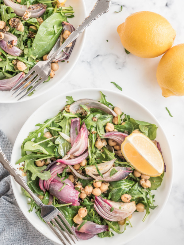 spinach and arugula salad in a white bowl with lemon