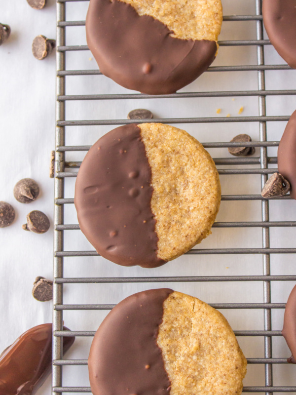 three half chocolate dipped cookies on a cooling rack