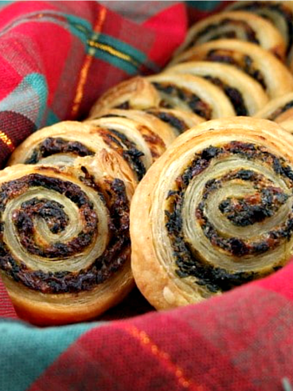 spinach and sundried tomato puff pastries in plaid napkin lined basket