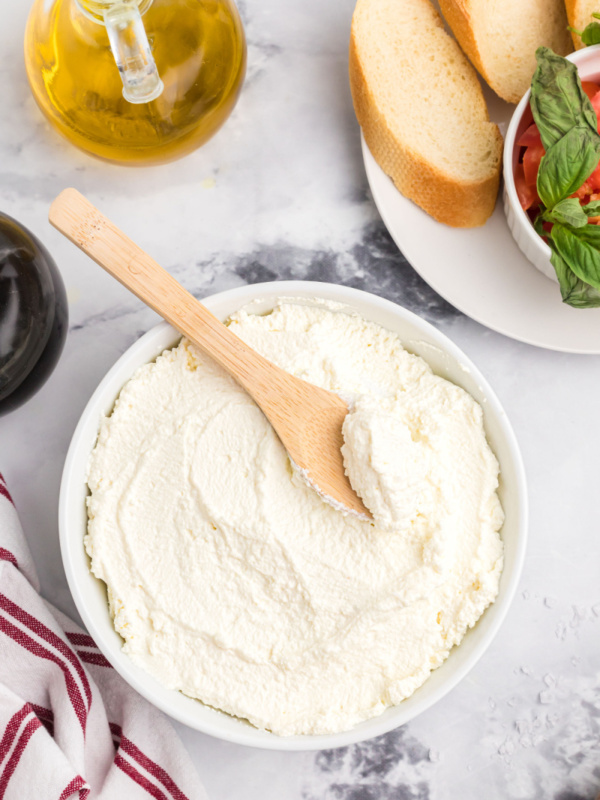 bowl of homemade ricotta cheese with wooden spoon