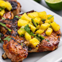 chili rubbed pork chops platter topped with grilled pineapple salsa