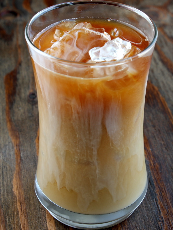 tall glass of iced coffee sitting on a wooden board