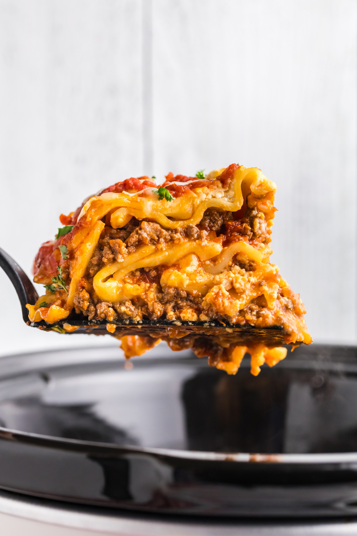 spatula holding slice of slow cooker lasagna