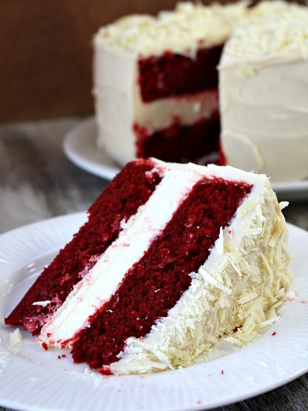 slice of red velvet cheesecake cake on a white plate with the cake in the background