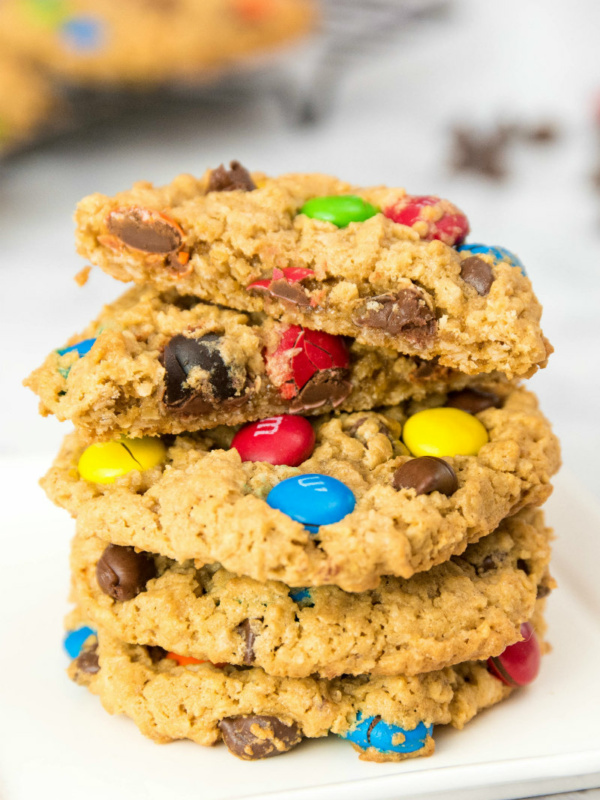 stack of monster cookies with the cookie on top split in half to show the inside