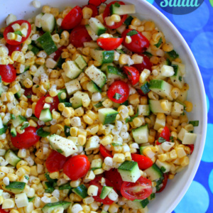 overhead shot of white bowl of fresh corn, tomato and zucchini salad set on a blue and green polka dot tablecloth