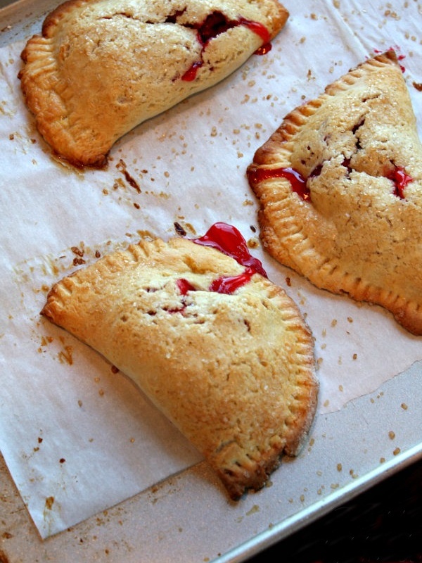 three berry hand pies on a baking sheet lined with parchment paper