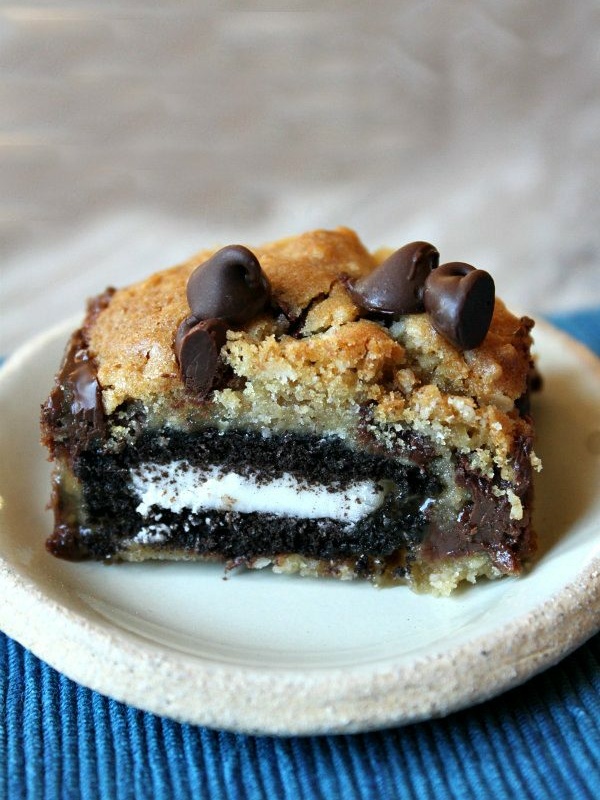 oreo and caramel stuffed chocolate chip cookie bar on a white plate set on a blue placemat