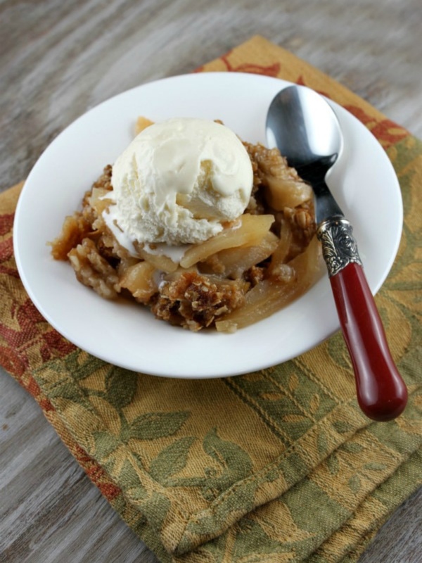 apple crisp topped with ice cream in a white bowl