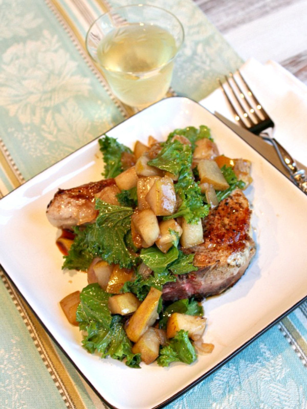 pean seared pork chops with pear on a white plate with glass of wine