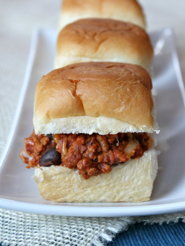 Three sloppy joe sliders lined up on a platter