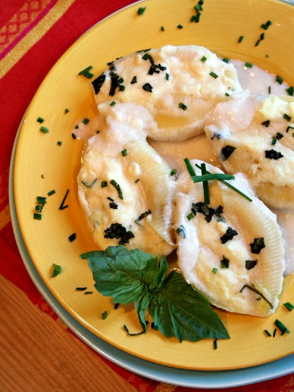 three cheese stuffed shells on a plate with cream sauce