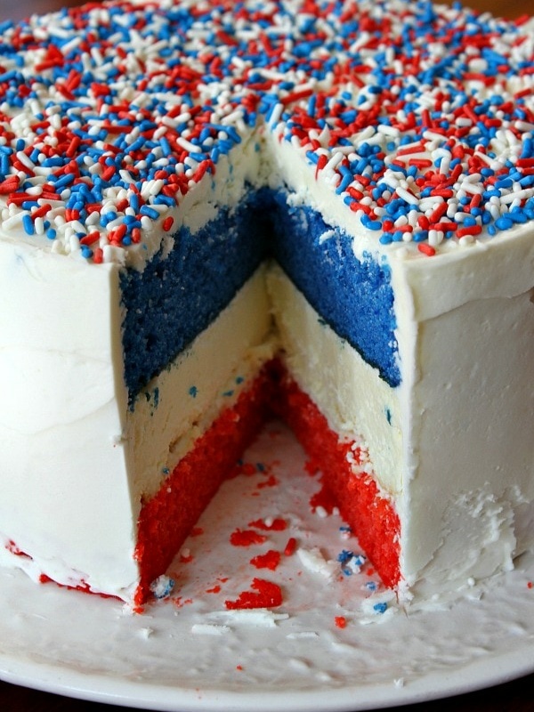 red, white and blue cheesecake cake sliced into to see the inside- displayed on a white plate