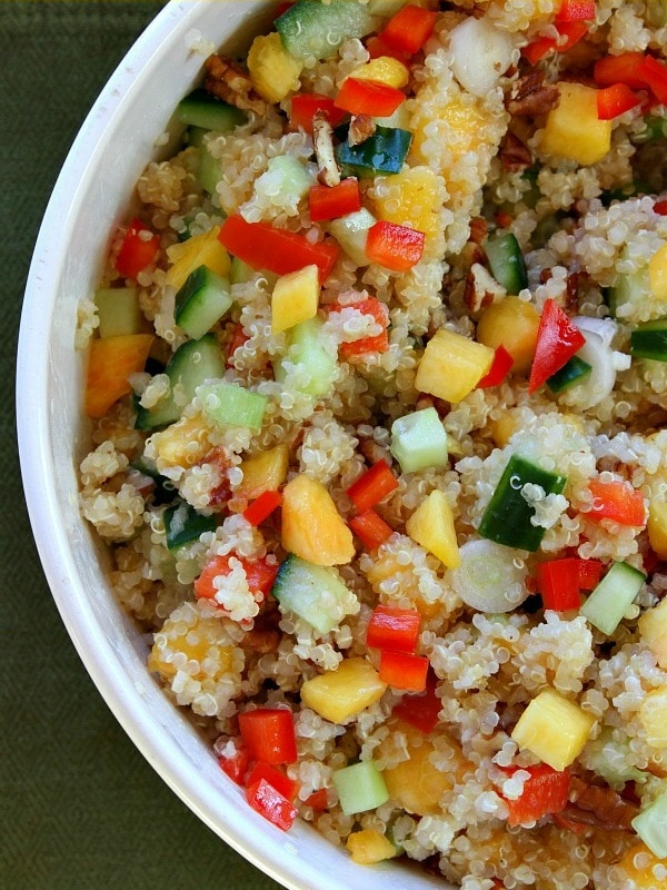 overhead shot of half of a peach and pecan quinoa salad in a white bowl