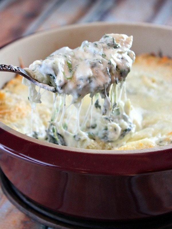 lightened up spinach artichoke dip spooning out of dish