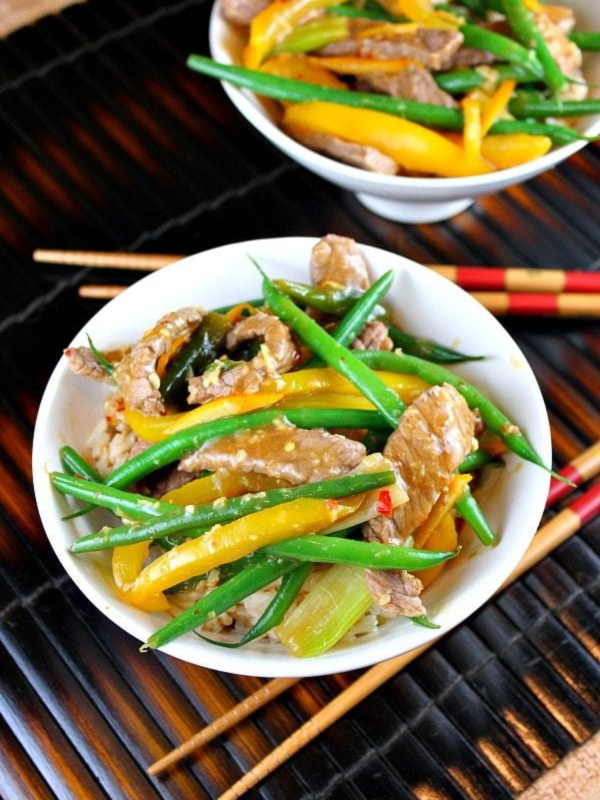 szechuan orange ginger beef in two bowls with chopsticks